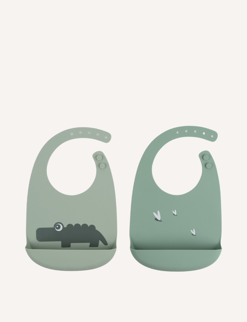 Two light green silicone baby bibs, one with a crocodile print and the other with small flies.