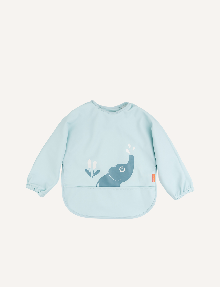 The Done by Deer Sleeved Pocket Bib is waterproof and features a light green, long-sleeve design with alligators, trees, and birds. It has a curved bottom edge, smooth fabric, gathered cuffs, and a small right-side tag—perfect for easy-to-clean mealtime fun.