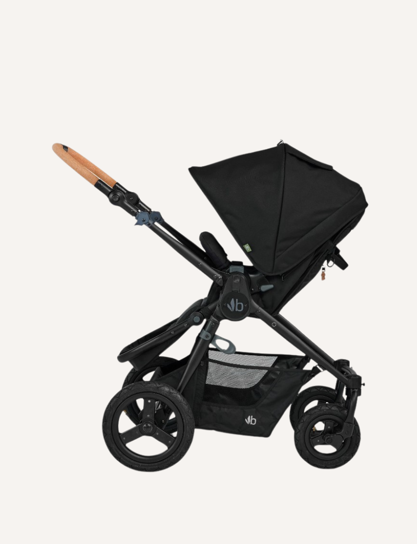 The Bumbleride ERA Pram by Bumbleride is a black baby stroller featuring a canopy and a brown handlebar. It comes equipped with four large wheels and a spacious undercarriage storage basket. The sturdy and adjustable frame makes it suitable for various terrains.