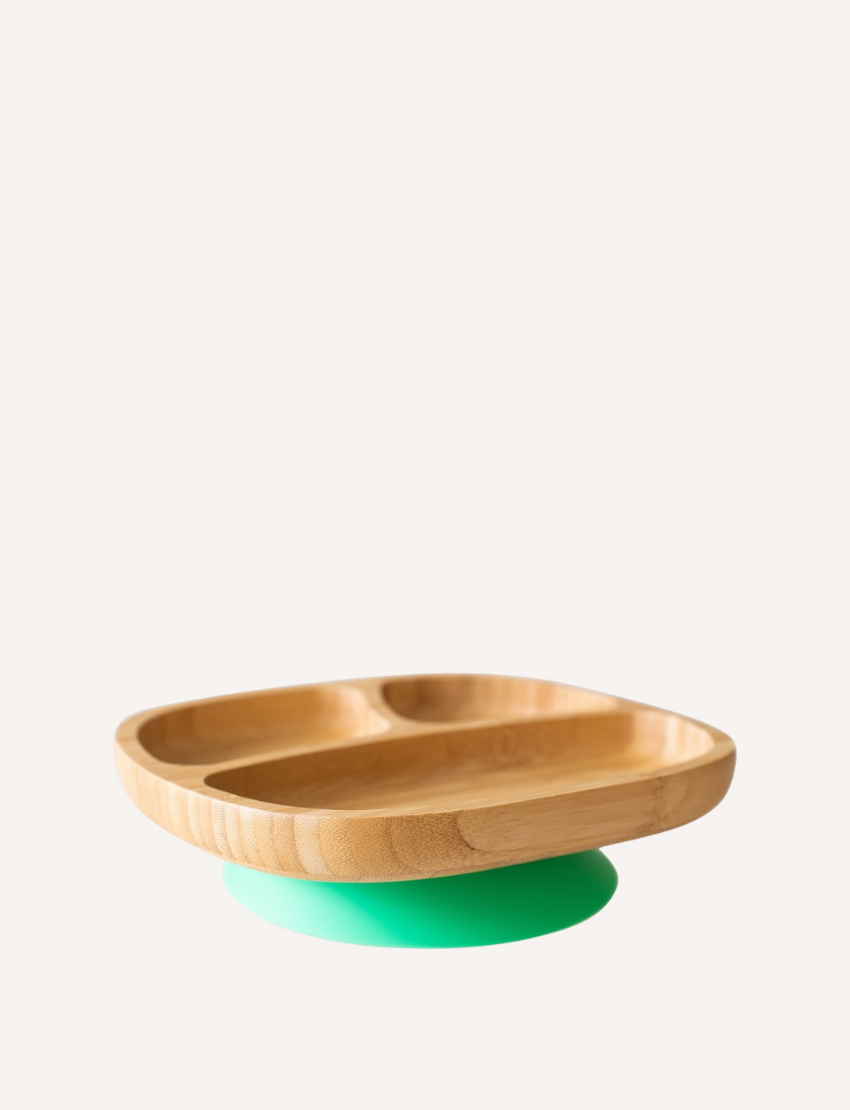 The Eco Rascals Organic Bamboo Suction Plate - Oval - Green showcases three compartments, rounded edges, and rests on a vibrant green silicone suction base, all set against a plain white background.