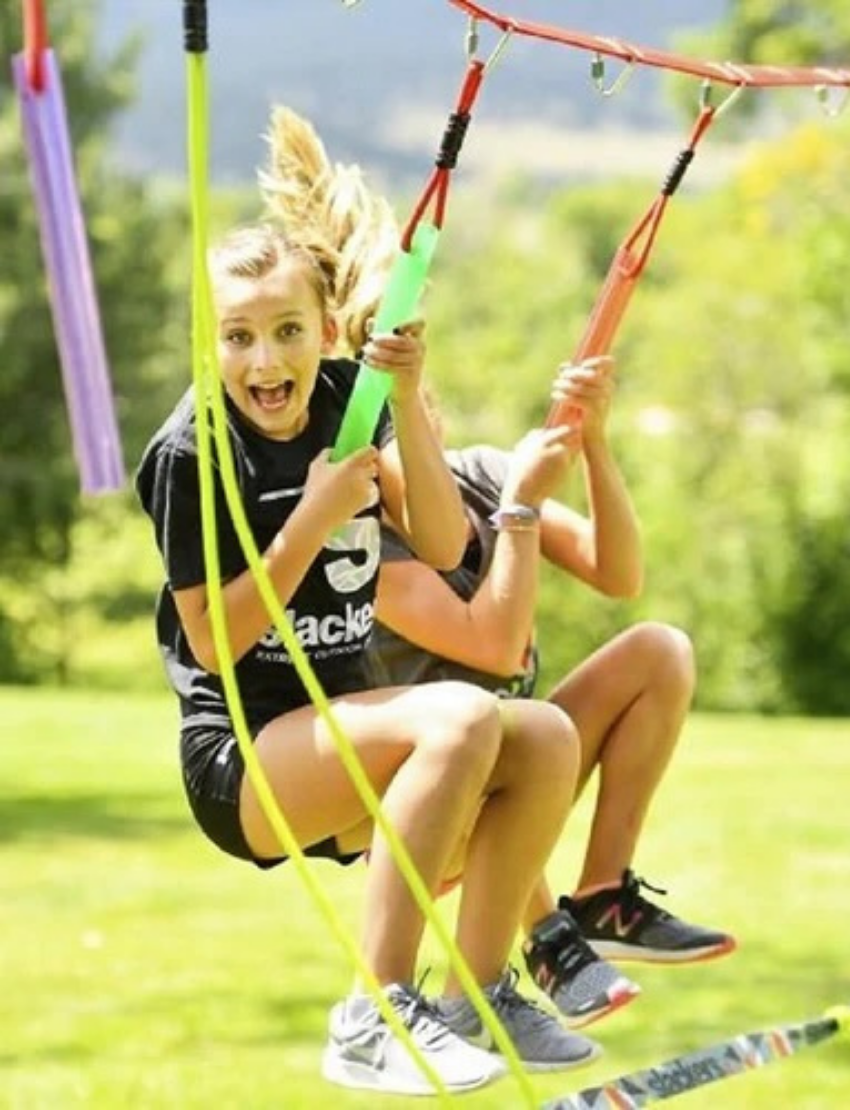 The image shows a rectangular box for a product called "Ropes Course" by Slackers. The box features an image of a person using the ropes course in an outdoor park setting. The sides of the box include product details and specifications.