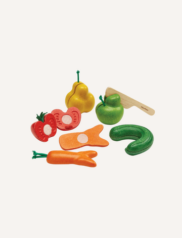 The PlanToys "Wonky Fruit & Vegetables" collection features a set of wooden toy fruits and vegetables, including a pear, apple, tomato, carrot, and cucumber, along with a small wooden knife. Designed to enhance fine motor skills, these brightly colored items are segmented to appear sliced and encourage discussions on reducing food waste.