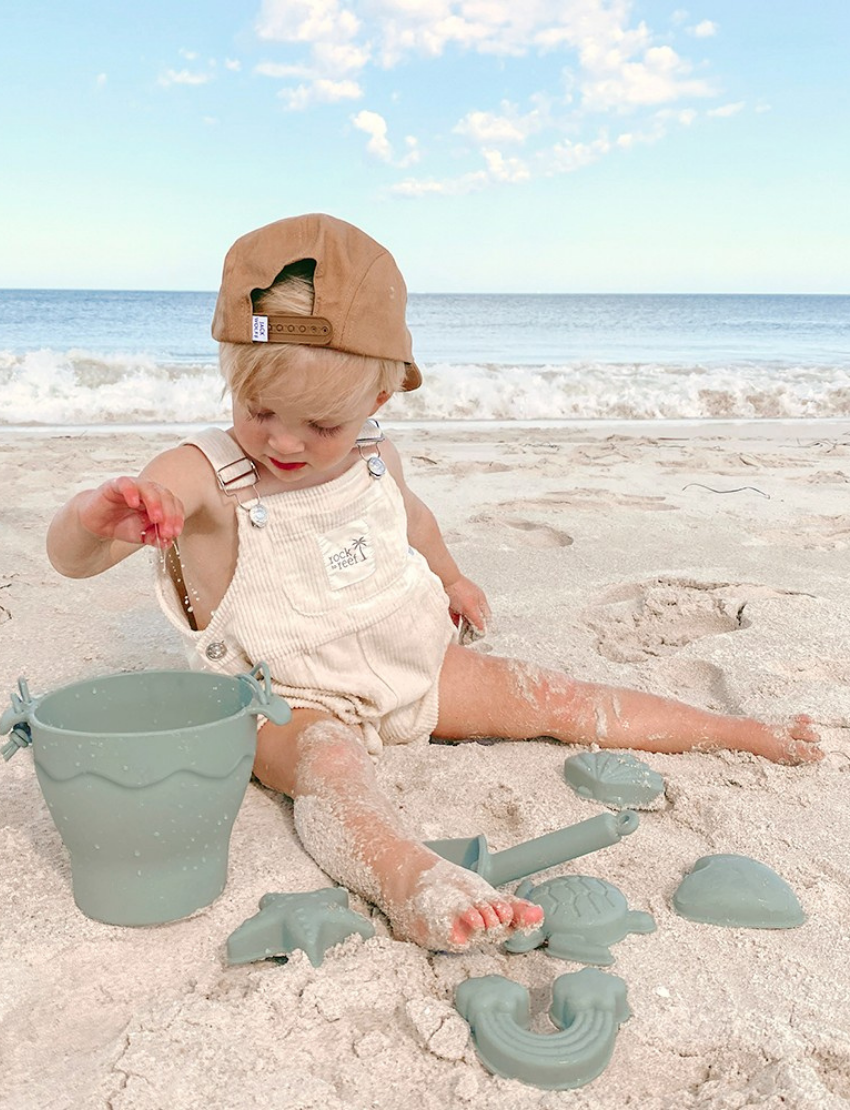 Playground's 8-Piece Bucket & Spade Set, featuring a yellow bucket with a handle, a small shovel, five sand molds in various shapes (sun, cloud, starfish, turtle, and crab), and a drawstring storage bag—all neatly arranged on a plain background.