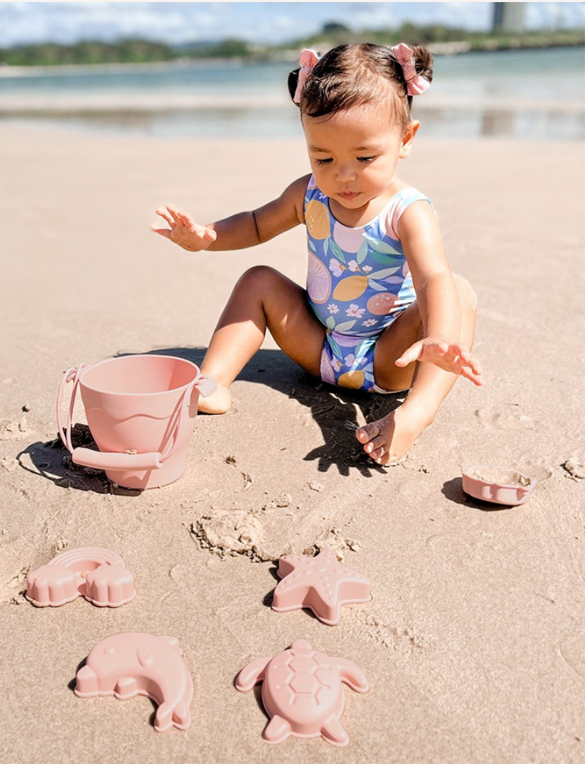 Playground's 8-Piece Bucket & Spade Set, featuring a yellow bucket with a handle, a small shovel, five sand molds in various shapes (sun, cloud, starfish, turtle, and crab), and a drawstring storage bag—all neatly arranged on a plain background.