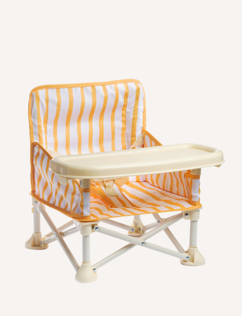 A pink and white checkered portable IZIMINI Baby Chair with a tray is set against a plain background. The lightweight, collapsible frame ensures easy transportation, making the high-chair adaptable for any outing or mealtime adventure.