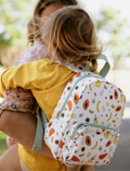 The IZIMINI Mini Backpack, featuring a cream-colored base adorned with a playful fruit pattern—including avocados, bananas, pineapples, and watermelons—is perfect for your toddler. It boasts mint-green straps and zipper pulls, a small exterior pocket, and plenty of space for little essentials.