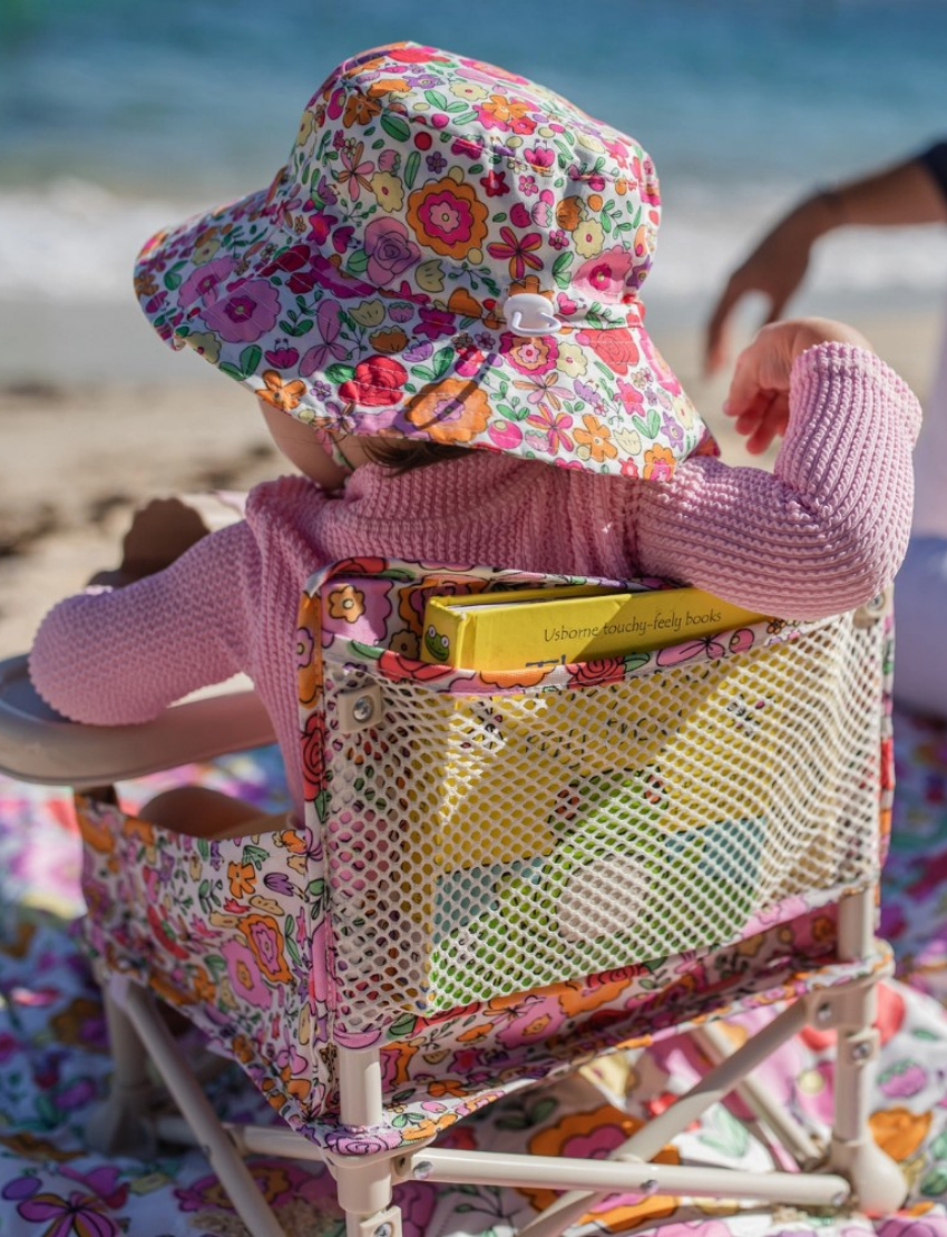 The IZIMINI Baby Chair is a lightweight and portable option, featuring a pink and white checkered fabric seat and a beige tray. It boasts a durable frame made of white plastic and metal, with secure, wide-set feet for enhanced stability.