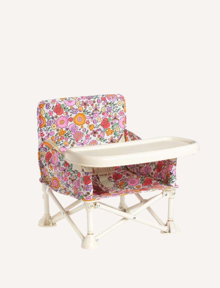 The IZIMINI Baby Chair is a lightweight and portable option, featuring a pink and white checkered fabric seat and a beige tray. It boasts a durable frame made of white plastic and metal, with secure, wide-set feet for enhanced stability.