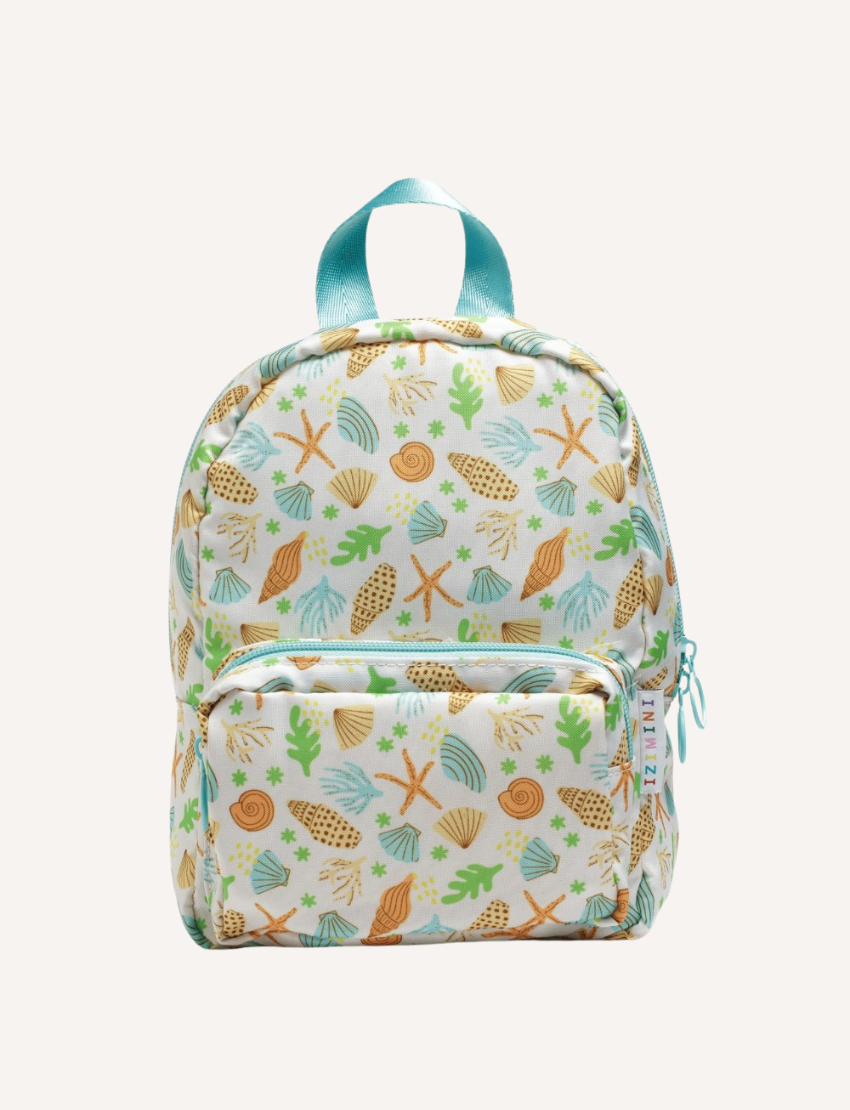 The IZIMINI Mini Backpack, featuring a cream-colored base adorned with a playful fruit pattern—including avocados, bananas, pineapples, and watermelons—is perfect for your toddler. It boasts mint-green straps and zipper pulls, a small exterior pocket, and plenty of space for little essentials.