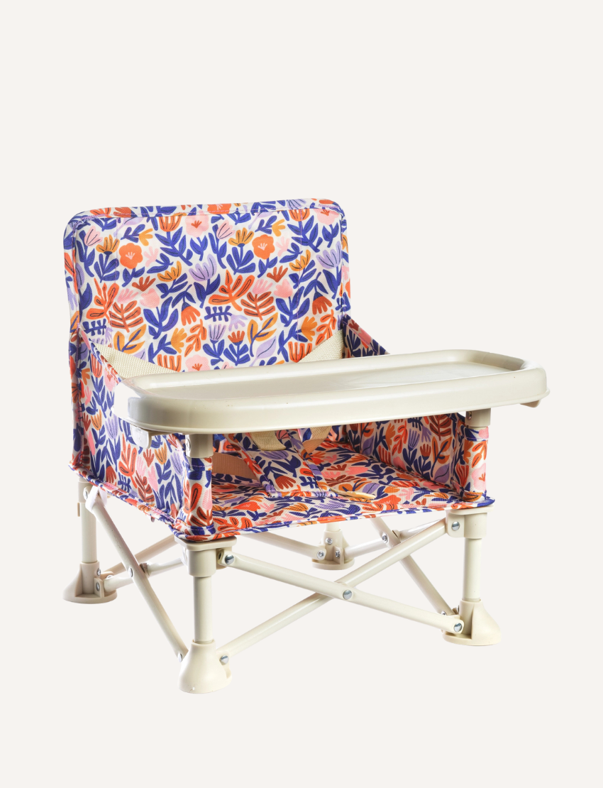 The IZIMINI Baby Chair features a lightweight, portable design with a foldable metal base and floral fabric in orange, blue, and purple, plus a beige plastic tray.