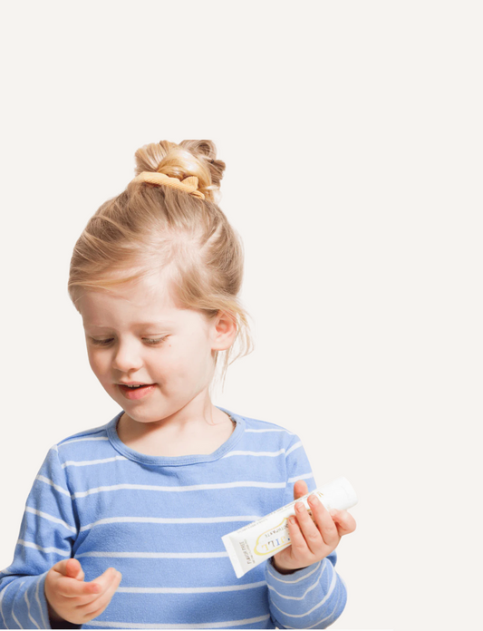 A white tube of Jack N' Jill Flavour Free Natural Toothpaste is displayed against a plain background. The tube, labeled as flavor-free, fluoride-free, and weighing 50g (1.76 oz), features illustrations of children.