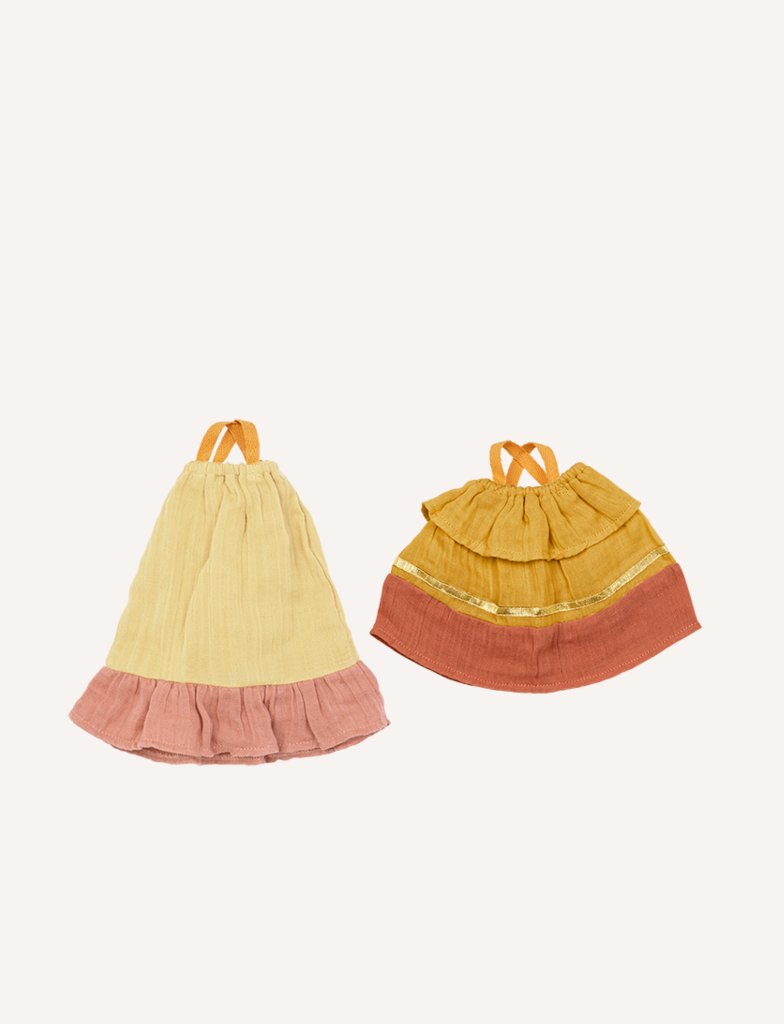 Two adorable Fabelab summer dresses from the Doll Clothes collection are displayed against a plain background. The dress on the left is yellow with a pink ruffled hem, while the dress on the right features an orange ruffled hem and golden trim. Both have orange straps for tying, making them perfect playtime outfits in children's fashion.