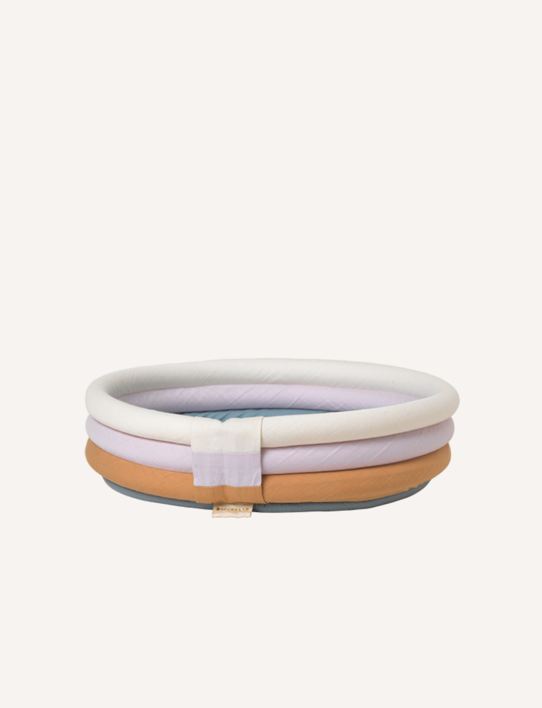 Discover the Fabelab Doll Accessories - Pool, a circular, multicolored pet bed with light purple, white, and tan layers in a charming quilted design. The bed features a fabric tag attached to the front and is perfect for imaginative play or as a mini pool for doll summer adventures. Displayed against a plain white background, this accessory adds fun and versatility to any playtime.