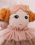 Doll Estelle, from the brand by Astrup, is a luxurious fabric doll with red hair. She is dressed in a floral outfit accented with a pink ruffled collar and comes placed next to a detachable pink tulle tutu and matching headband against a plain background. Perfect for imaginative play.