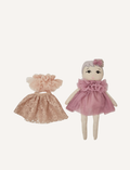 The Doll Fleur and Change of Outfit by Astrup features a soft fabric doll with light skin, embroidered eyes, short white hair adorned with a small flower, dressed in a purple tulle outfit. To the left of the doll lies a separate pink lace and tulle dress displayed on a flat surface.