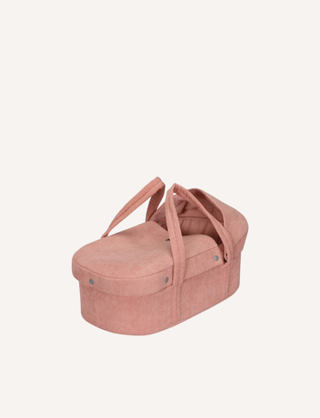 A Doll Carrycot - Blush 42cm by Astrup, crafted from pink corduroy and equipped with handles, showcases a soft, rounded design. It includes a removable hood that partially covers the interior. This charming doll’s carrycot is presented against a plain, off-white background.