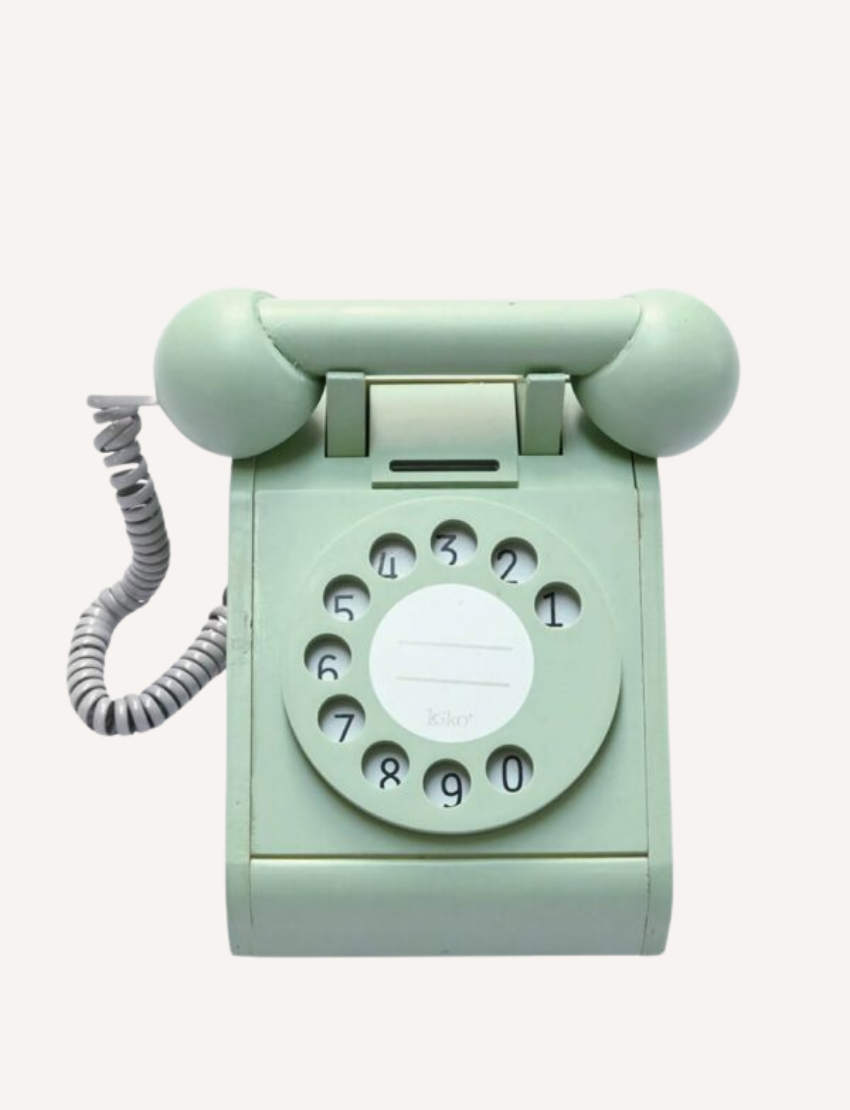 A vintage-style green toy telephone with a rotary dial and coiled cord.