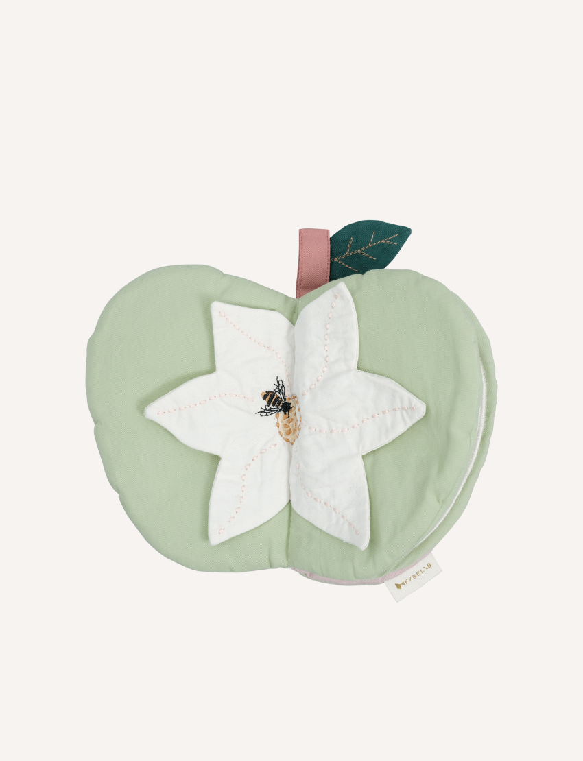 Closed green fabric apple book with a white flower and bee applique on a light background.