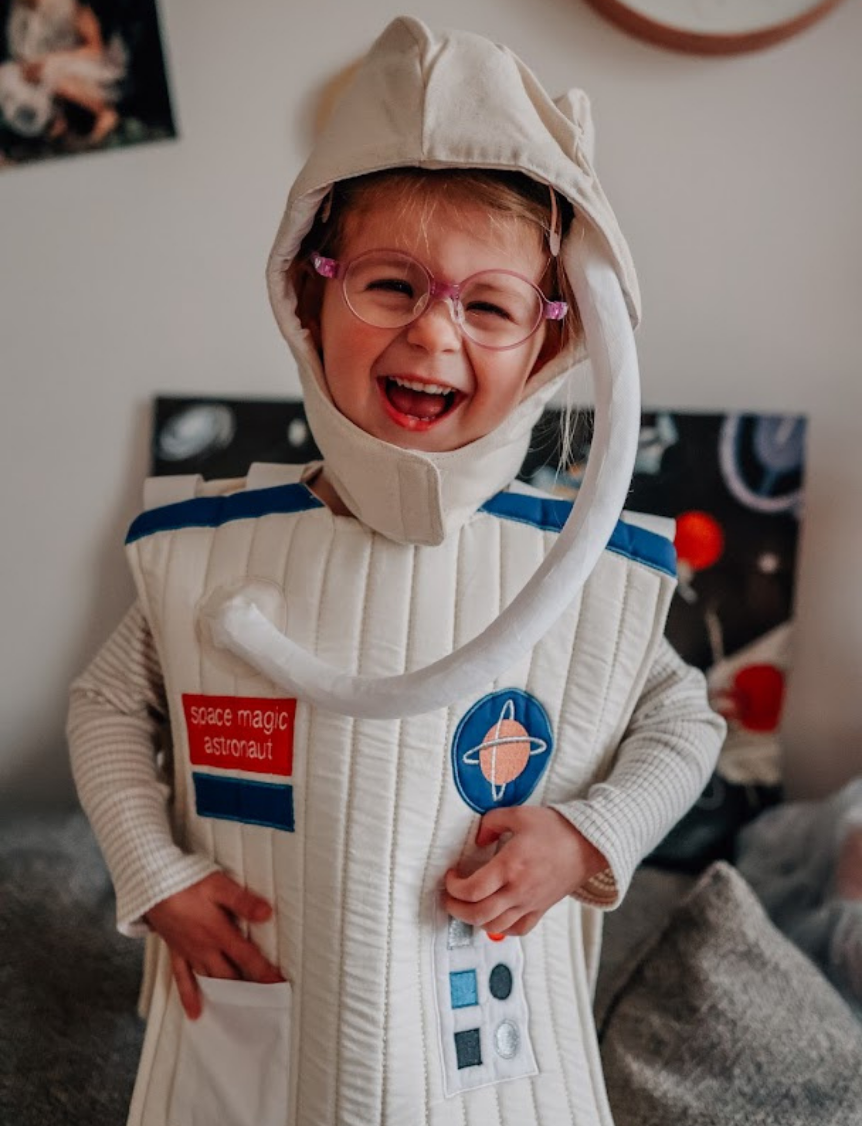 Introducing the Dress-up - Little Astronaut Set by Fabelab—an enchanting children's outfit featuring a sleeveless white vest made from organic cotton, adorned with a vibrant red and blue design and various button patterns. Labeled "space magic astronaut," this set also includes a matching white helmet. Perfect for Halloween costume adventures or everyday imaginative play!