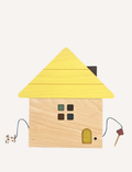 The Tsumiki House of Blocks by kiko+ and gg* features a delightful wooden toy house with a yellow roof. This charming house includes a small window with four panes, a rectangular door, and two strings—one ending in a small dog and the other in a tree. It comes as part of a 41-piece set.