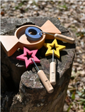 The image displays the Amechan Magical Bubble Wands by kiko+ and gg*, featuring three wooden wands and one wooden dish, ideal for eco-friendly bubble fun. The wands have star-shaped tops in red, yellow, and blue, with handles engraved 