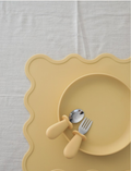 A light-colored rectangular Placemat from Rommer Co featuring wavy edges, crafted from non-toxic, BPA-free, FDA-approved silicone. The white background highlights the product as the focal point.