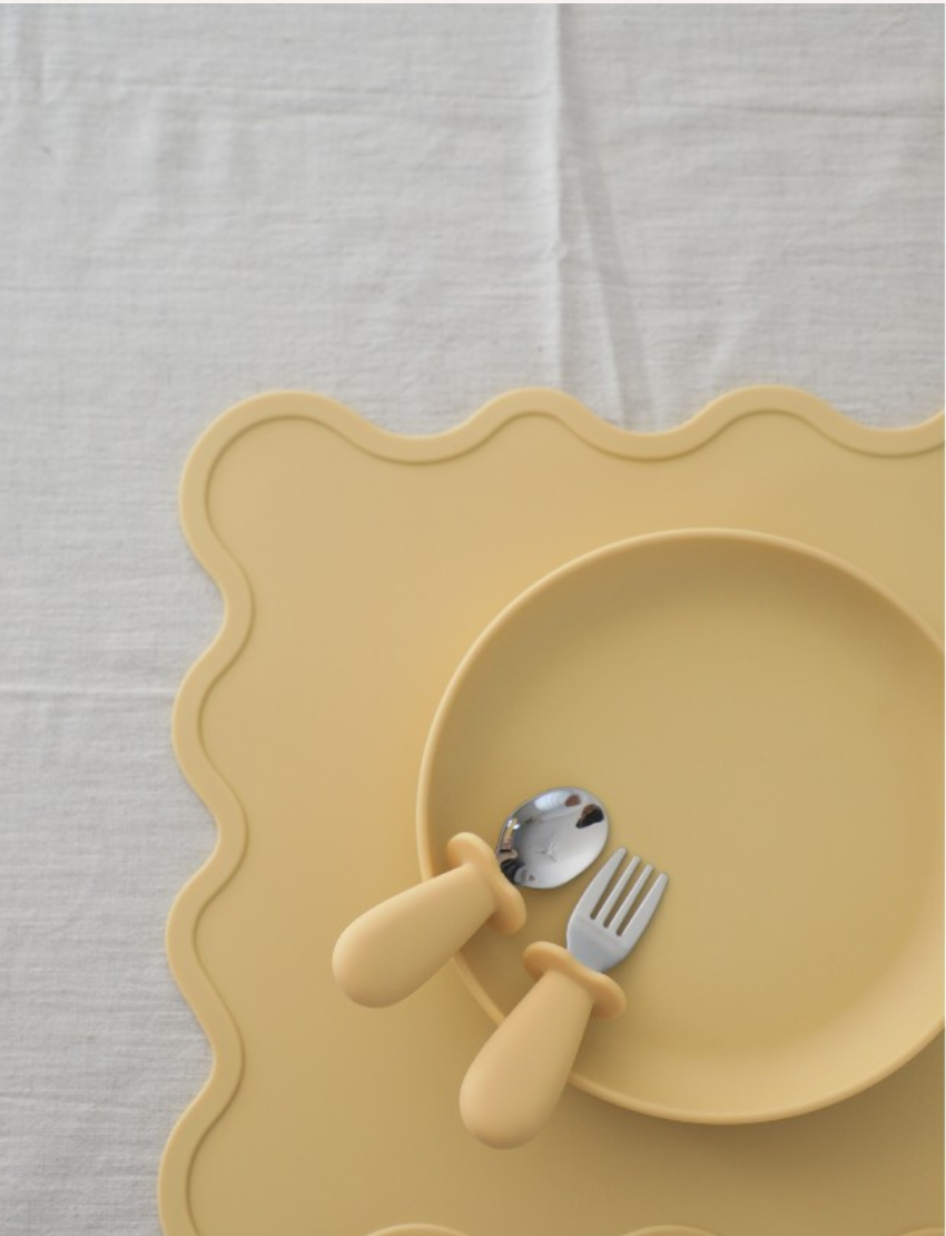 A light-colored rectangular Placemat from Rommer Co featuring wavy edges, crafted from non-toxic, BPA-free, FDA-approved silicone. The white background highlights the product as the focal point.