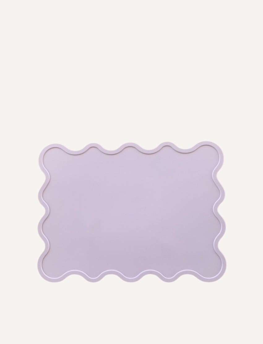 A light-colored rectangular Placemat from Rommer Co featuring wavy edges, crafted from non-toxic, BPA-free, FDA-approved silicone. The white background highlights the product as the focal point.