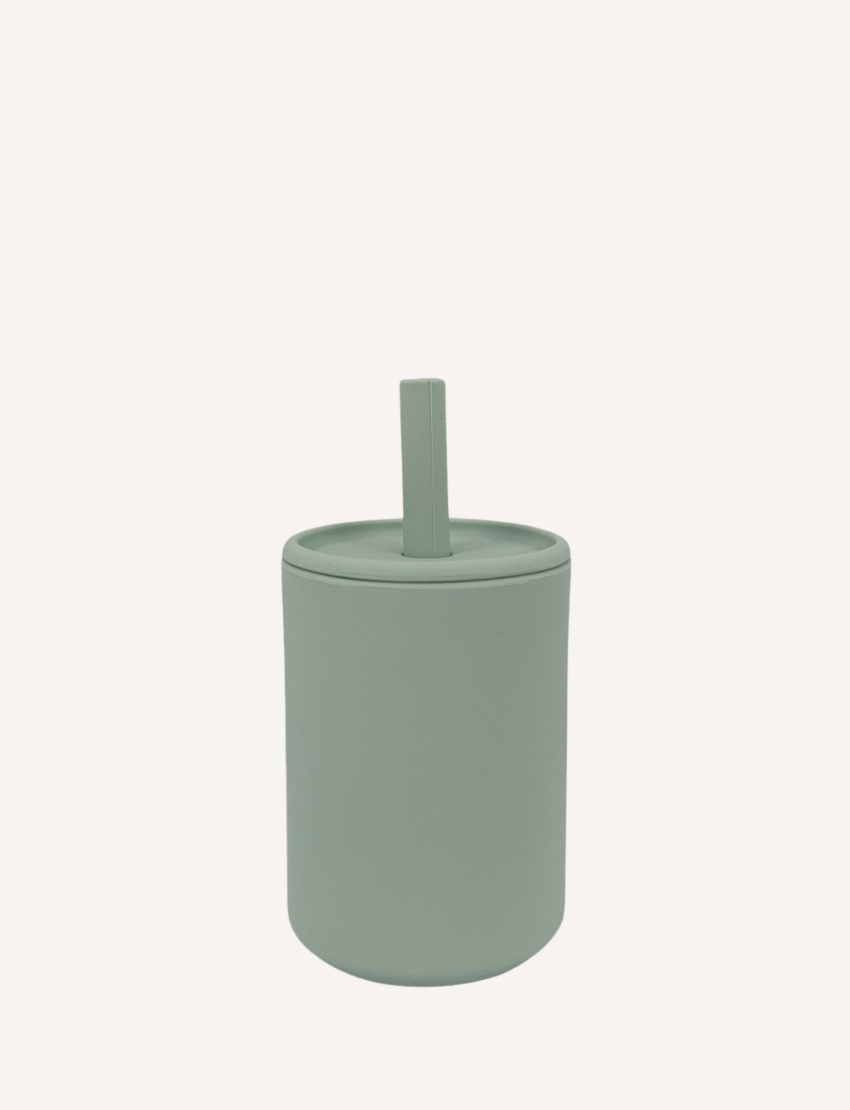 The Sippy Cup by Rommer Co is a light green, cylindrical container made of premium silicone, featuring a matching lid with a vertical handle on top. The smooth, matte material ensures it’s easy to clean. The product is showcased against a white background.