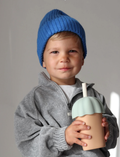 A young child wearing a blue knit cap and a gray zip-up jacket is holding a Rommer Co Smoothie Cup Sea Mist. The child has a neutral expression and is looking slightly off camera. The background is plain and gray.