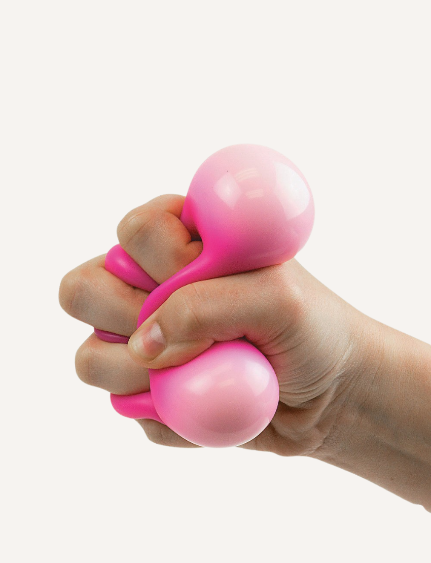 The Sensory Genius Sqwooze ball, a smooth, round, solid pink ball made of a soft material like rubber or silicone, is centered against a plain white background.