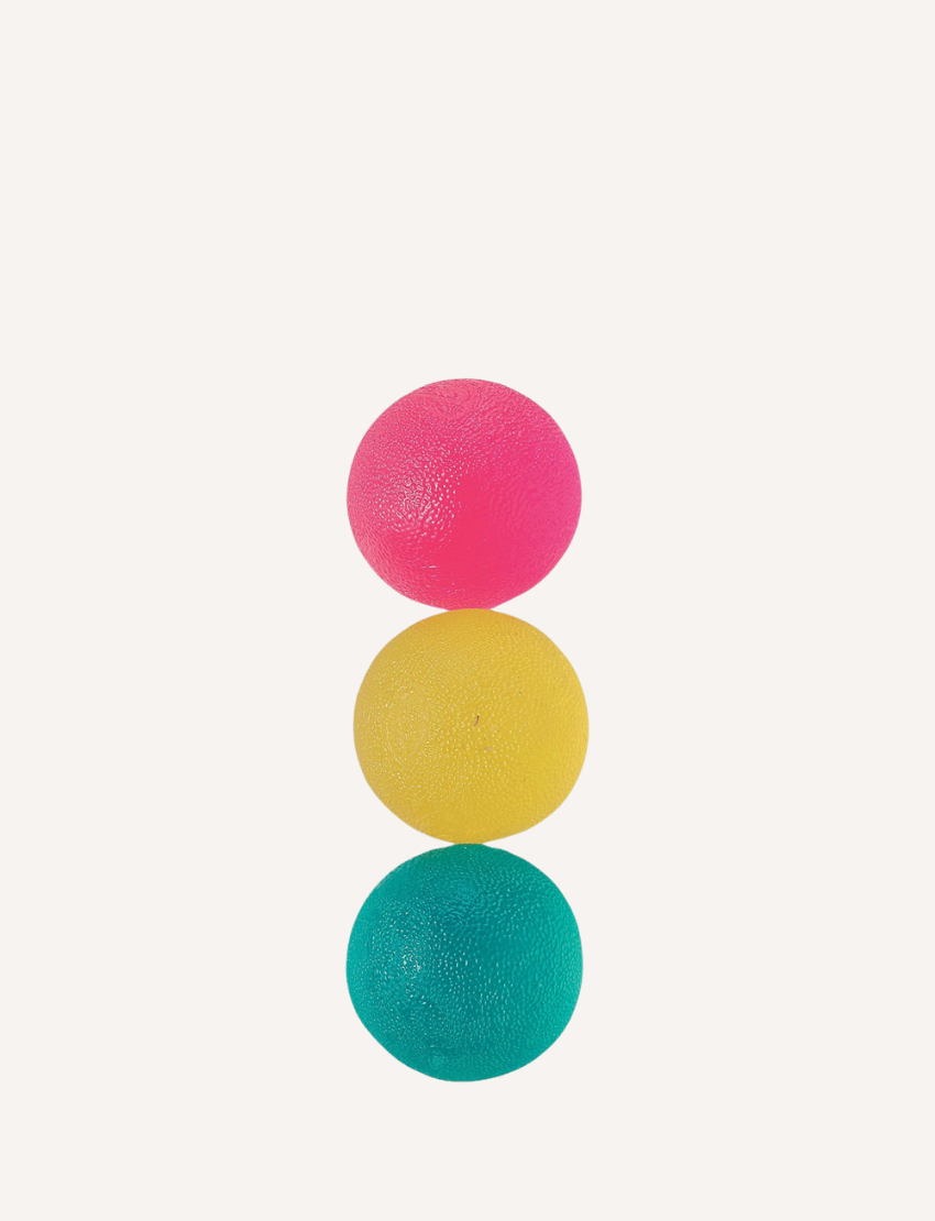 Three stress balls from Sensory Genius are stacked vertically against a plain white background. From top to bottom, the textured rubber balls in this set of three are colored pink, yellow, and teal.