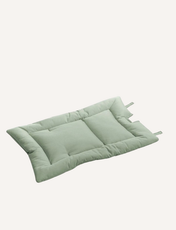 The High Chair Cushion - Sage by Leander is a rectangular, light green cushion with tufted details and two fabric loops on one side. The cushion appears plush and is placed on a plain, light-colored background.