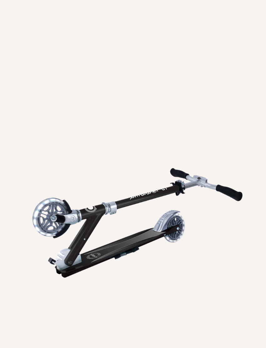 The Flow Element Scooter with Lights by Globber, featuring a sleek black and silver design, is shown. It has handlebars with black grips, a stand, and a rear brake. The scooter is positioned against a white background.