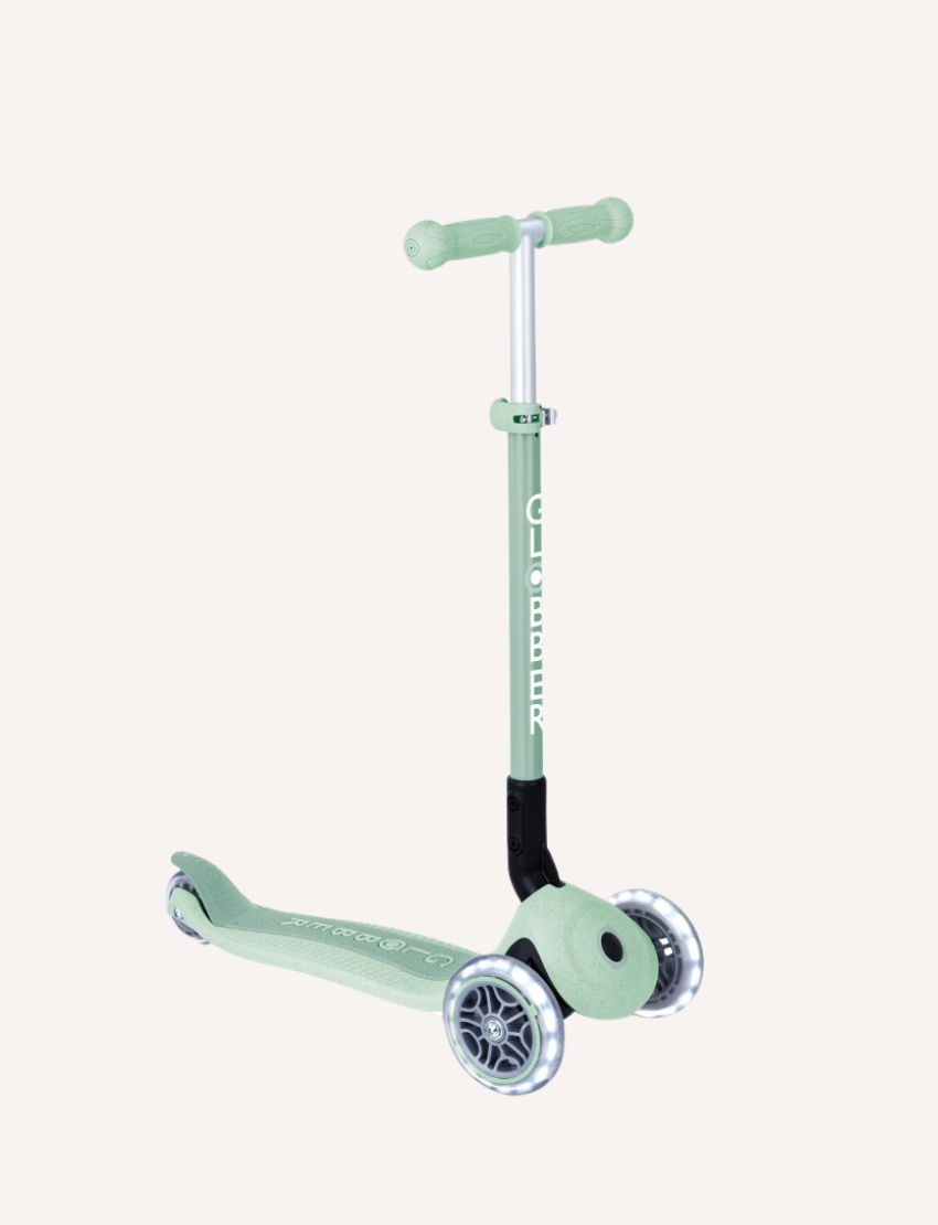 The Globber Ecologic Primo Foldable Scooter with Lights in light blue has LED front wheels, a three-wheel design, and an adjustable aluminium T-bar. The deck displays "GLOBBER," and larger front wheels provide a sleek design suited for young riders.