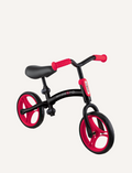 The Globber Go Bike Duo Balance Bike is a small, black and red toddler bike with no pedals, featuring EVA foam wheels. It has a black frame, a red adjustable handlebar, a black seat, and red wheels. The bike also includes a small footrest platform on the frame.