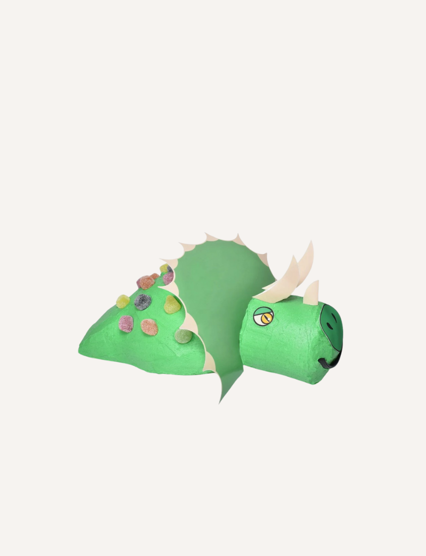 A whimsical, cartoonish green dragon, made from papier-mâché with colorful spots and white spikes, has a playfully painted face. Perfect for creative inspiration or as a themed birthday cake model using edible paper and the Shape Tins Australia Cake Decorating Set.