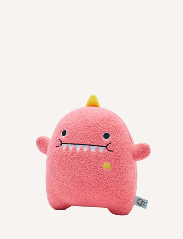 The Noodoll Plush Toy - Missdino is a pink plush toy shaped like a rounded monster. It features small arms, two white felt teeth, black eyes, and a small yellow heart embroidered on its right side. The toy also has a yellow felt horn on top and a small tag attached at the bottom left.