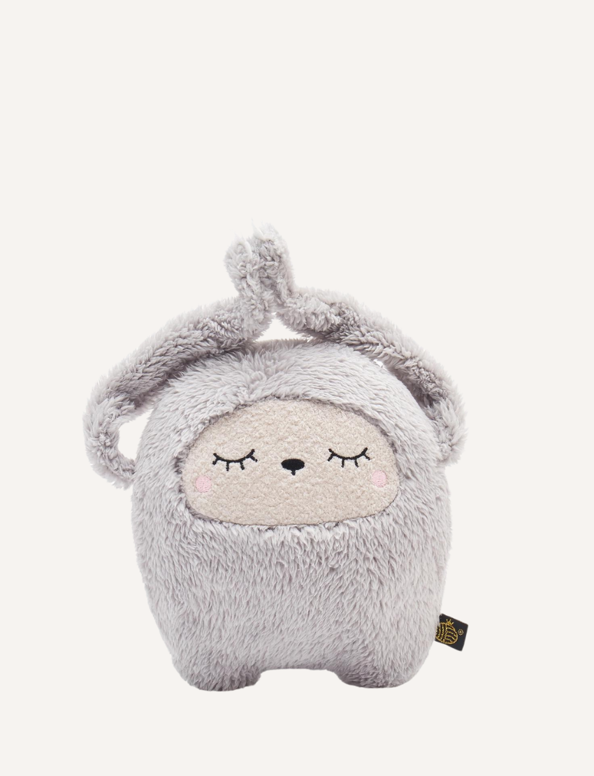 Fluffy grey plush toy with sleepy eyes and ears tied on top, on white background.