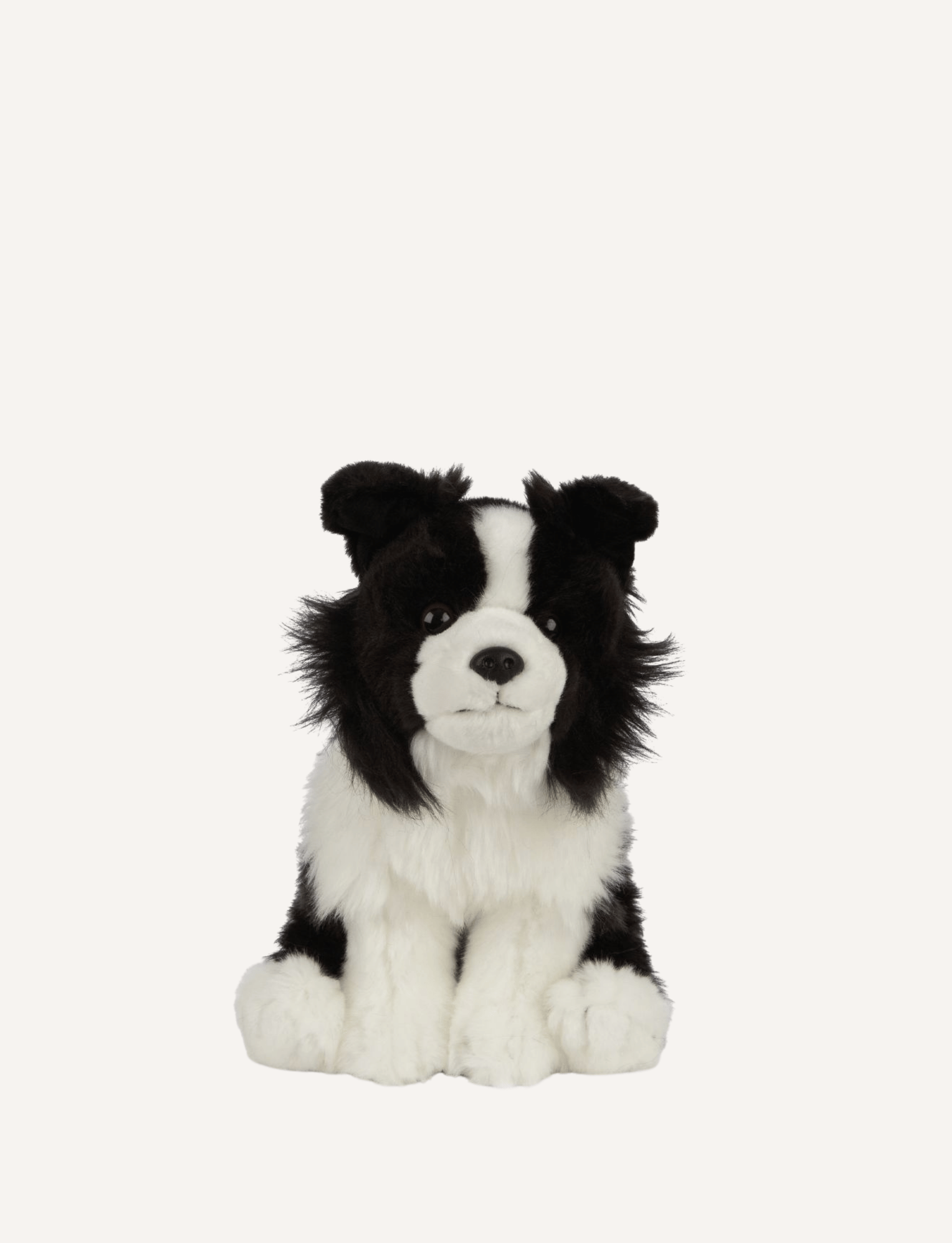 The Living Nature Border Collie, a soft toy by Living Nature, is depicted in a sitting position against a plain white background. Crafted from recycled plastics, this eco-friendly toy features fluffy fur and a calm facial expression, making it a delightful way to share educational animal facts.