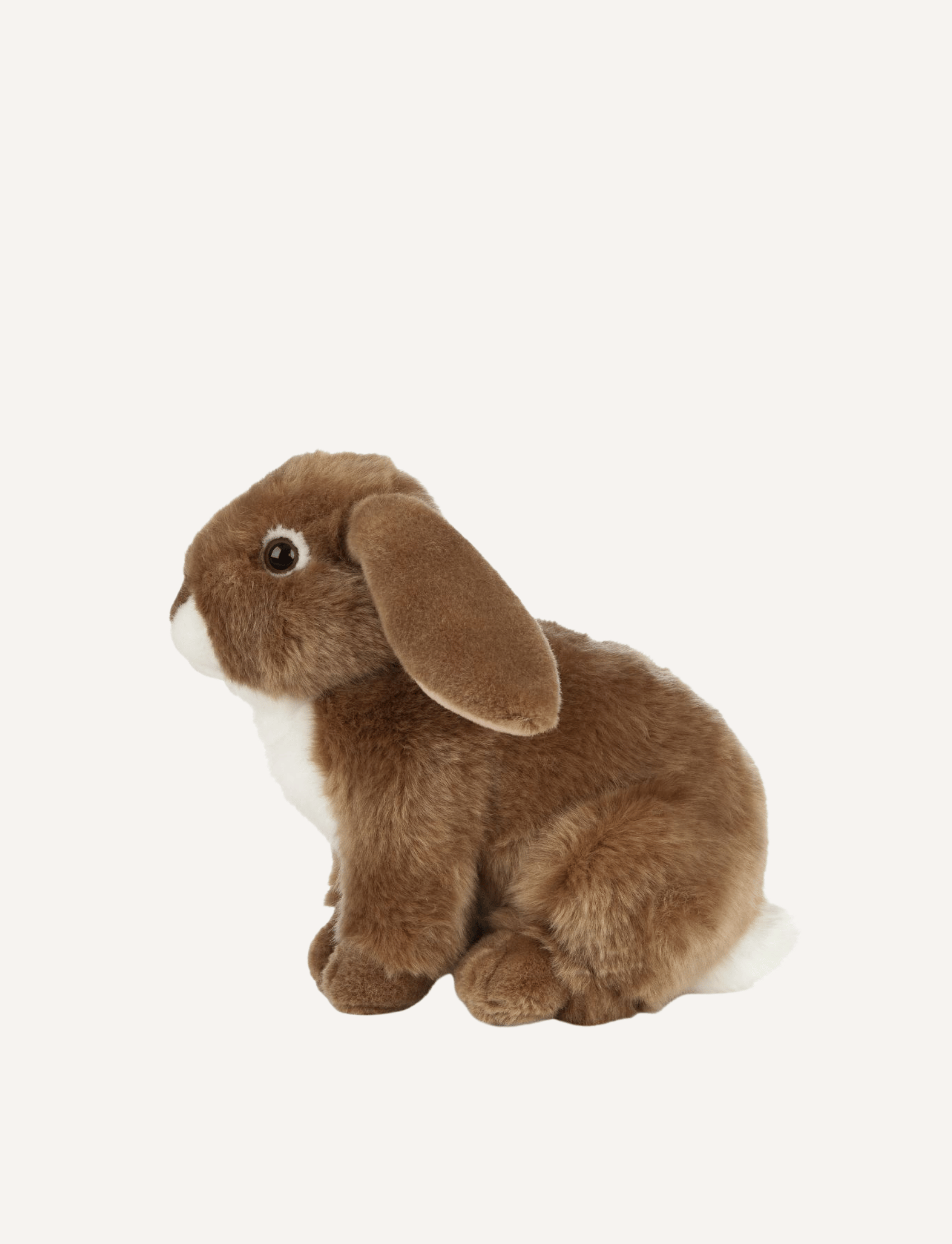 The Living Nature Brown Rabbit, a soft toy by Living Nature, is shown in a side profile on a plain white background. The toy features soft, brown fur, a white underbelly, dark eyes, and long floppy ears. It is made from recycled plastics to promote sustainability.