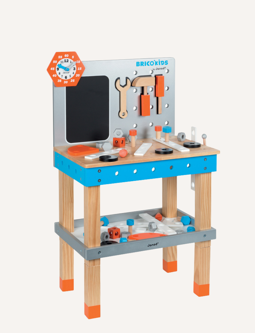 The image depicts a box containing the BricoKids DIY Giant Magnetic Workbench by Janod, designed for children aged 3 to 8. The packaging includes illustrations of the assembled workbench complete with tools, a chalkboard, and storage options, along with the brand logo and age recommendation clearly visible.