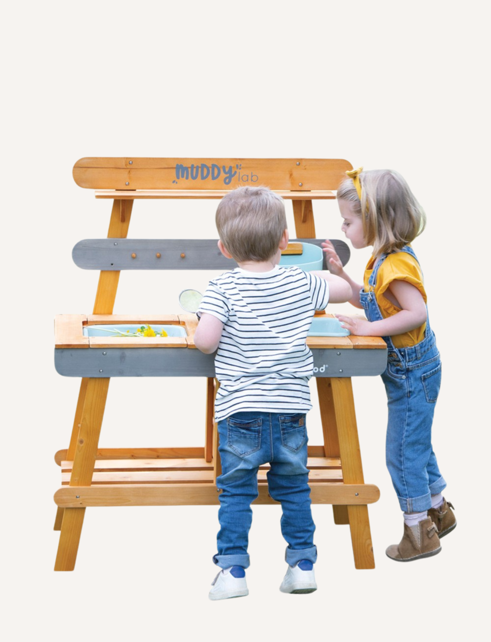 Janod's "Muddy Lab Outdoor Kitchen" is a boxed toy set that includes an outdoor wooden kitchen crafted from FSC certified wood. It features shelves, hooks for utensils, and an attached water dispenser. The packaging displays images of the assembled product alongside children joyfully playing with the Muddy Lab Outdoor Kitchen.