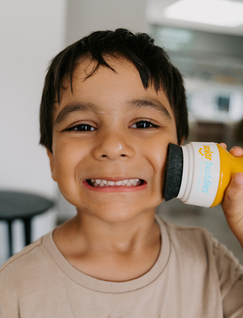 An image of the Solar Buddies Sunscreen Applicator by Solar Buddies. The product features a yellow and white handle with a blue removable cap and a black sponge applicator. The accompanying packaging is blue and white, highlighting key features such as "Easy to use," "Less mess," and "Refillable.