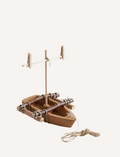 The HABA Cork Boat Kit includes a small model raft constructed from unsinkable cork and sticks, featuring an eco-friendly green leaf sail fastened with clothespins. It also comes with a piece of twine attached to the raft for easy maneuvering.