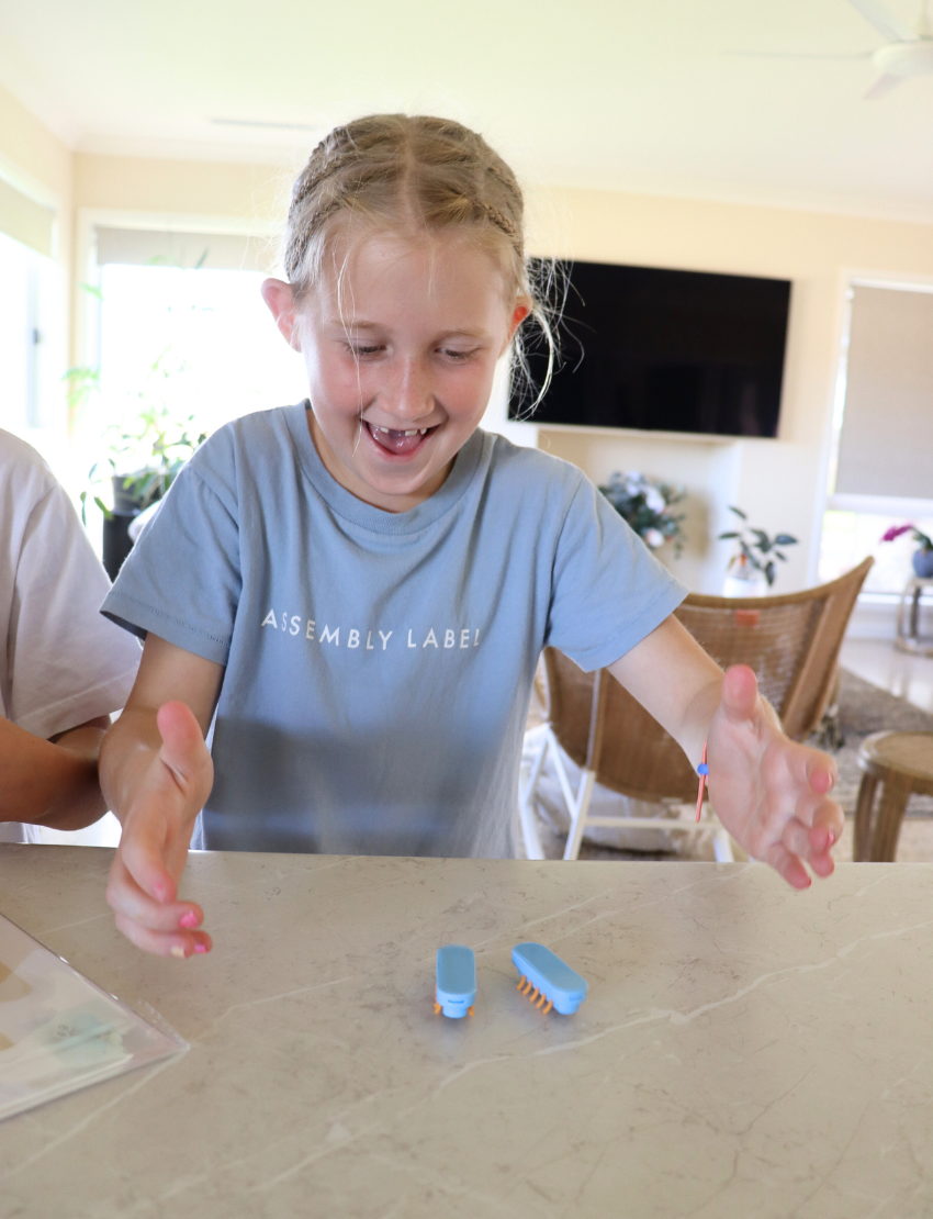 Introducing "Walking Robots - 3D Pen Activity" by The Play Way. This DIY motor toy set comes in a box adorned with illustrations of a bug and a 3D printing pen, complete with flexible legs for crafting your own walking robots. It includes "10 stencils" to help inspire the creation of moving creatures that enhance hand strength. The vibrant background is decorated with green leaves, perfect for sparking creativity.