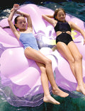 A person in a black swimsuit relaxes on a large, pastel lilac Luxe Lie-On Float by Sunnylife, perfect for pool parties and trendy floats.