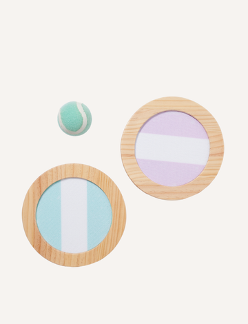 The Catch Ball Set - Rio Sun Multi by Sunnylife includes two round wooden paddles adorned with blue and lavender stripes, elegantly set against a light backdrop. A small green and white tennis ball floats above, inviting play.