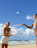 Two paddles from the Sunnylife Pickleball Set, featuring green and white stripes, are placed side by side. A green pickleball with holes is situated nearby on a simple white background.