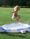 The Kids Sprinkler Mat Into the Wild - Blue by Sunnylife is displayed. This inflatable children's pool, designed in the shape of a chameleon, showcases a blue and white color scheme with intricate details including a tail, legs, and a chameleon head on one side. Currently, the pool is deflated and laid out flat.